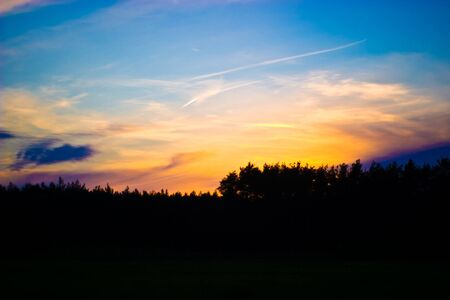 occurring yellow sun behind the clouds on a warm evening の写真素材