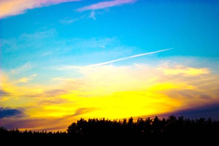 occurring yellow sun behind the clouds on a warm evening の写真素材