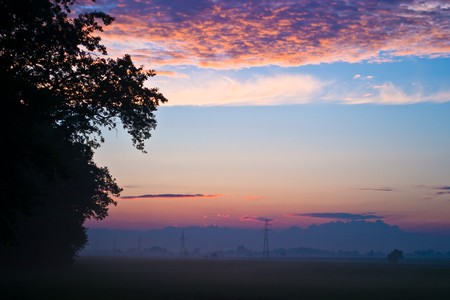 occurring yellow sun behind the clouds on a warm evening の写真素材