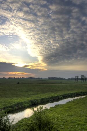 occurring yellow sun behind the clouds on a warm eveningの写真素材