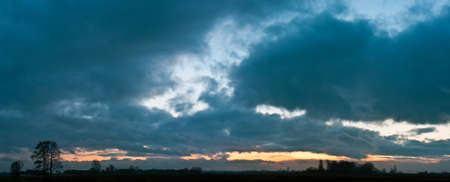 occurring yellow sun behind the clouds on a warm eveningの写真素材