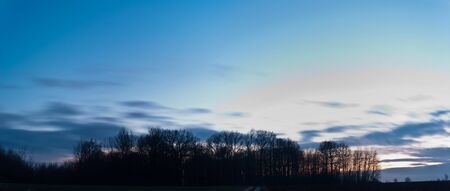 occurring yellow sun behind the clouds on a warm eveningの写真素材