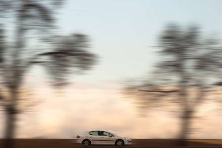 car on road between yellow and green trees with cloudy skyの写真素材