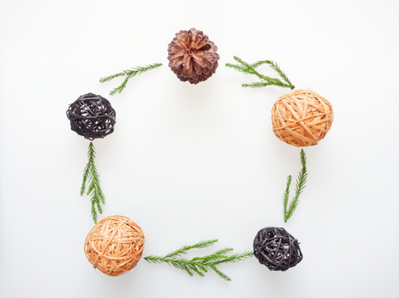 Christmas decoration or ornament laid in circle frame composed of green pine branch, brown pine...
