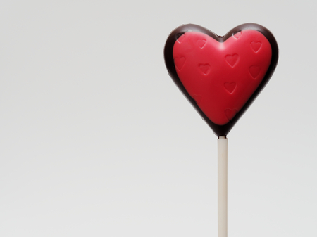 Heart shape chocolate lollipop with red color and heart stamp isolated over white backgroundの写真素材