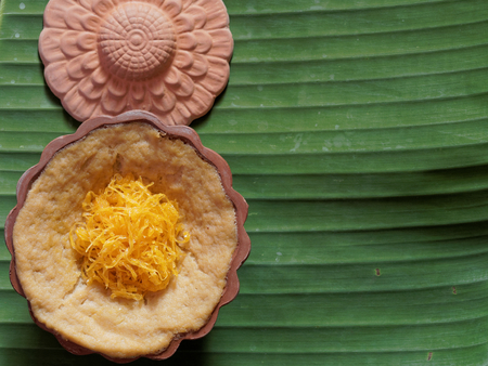 Thai dessert, egg custard with sweet sticky rice topped with golden threads, on banana leaf backgroundの写真素材