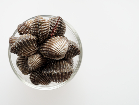 A group of raw cockle, ark shell, in a glass bowl isolated on white backgroundの写真素材
