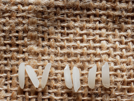 White raw rice in pattern over brown sackcloth background