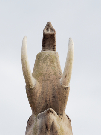 Ant eye view of elephant statue show the lower parts of neck, tusks, and trunk over pale blue sky backgroundの写真素材