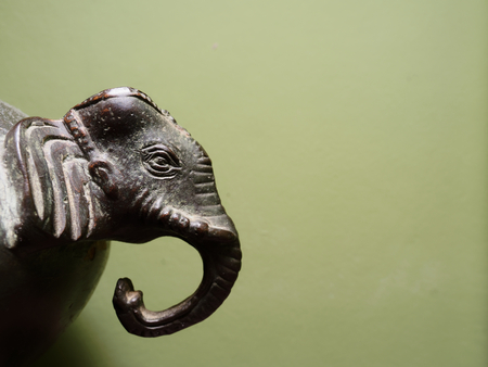 Interior or decoration in antiques, vintage, or retro style of elephant head over dark green background with concepts of relaxation, wellness, and calm, or in service, hotel, and leisure industryの写真素材