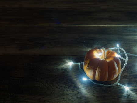 White decoration lights with yellow and orange pumpkins over dark wooden surface with space used as background, wallpaper, or backdrop in Halloween, festival, ornament and decoration themeの写真素材