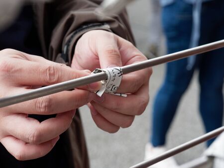 TOKYO, JAPAN - SEPTEMBER 28, 2017 : A tourist who select a bad fortune from Japanese fortune telling strip, Omikuji, tying his bad fortune paper with a pole to leave it at Sensoji temple, Asakusaのeditorial素材