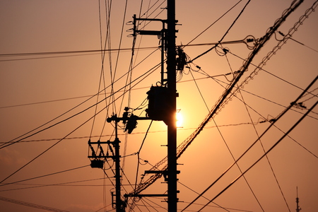 electricity poles against evening sunの写真素材