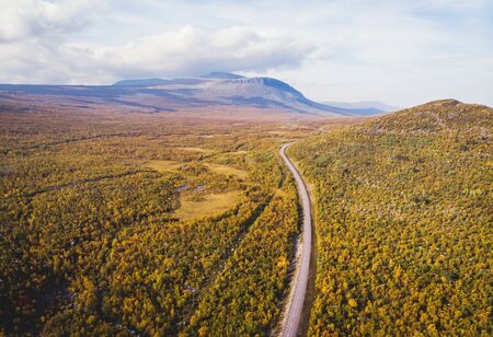 Aerial sunny fall autumn view of Abisko National Park, Kiruna Municipality, Lapland, Norrbotten County, Sweden, shot from drone, with Abiskojokk river, road and Nuolja mountainの写真素材