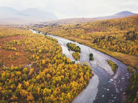 Aerial sunny fall autumn view of Abisko National Park, Kiruna Municipality, Lapland, Norrbotten County, Sweden, shot from drone, with Abiskojokk river, road and Nuolja mountainの写真素材