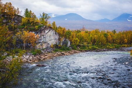 Sunny fall autumn view of Abisko National Park, Kiruna Municipality, Lapland, Norrbotten County, Sweden, with Abiskojokk river, road and Nuolja mountain, near border of Finland, Sweden and Norwayの写真素材
