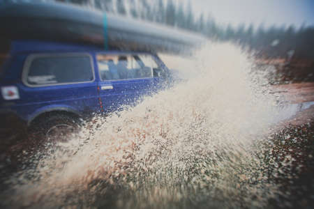 Suv offroad 4wd car rides through muddy puddle, off-road track road, with a big splash, during a jeeping competitionの写真素材