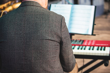 Concert view of a musical keyboard piano player during musical jazz band orchestra performing, keyboardist hands during concert, male pianist on stage, hands close-upの写真素材