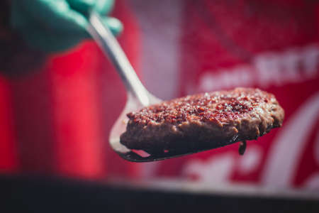 Process of cooking classic burgers with beef on open-air, view of chef hands in gloves with variety of fillings and ingredients on wooden desk and stove, summer dayの写真素材