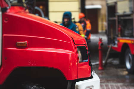 Group of fire men in uniform during fire fighting operation in the city streets, firefighters with...