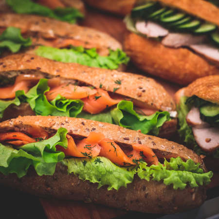 Beautifully decorated catering banquet table with different food snacks and appetizers setting with sandwiches, triange, croissant club submarine sandwich, on wooden plate, party or celebrationの写真素材