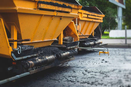 Process of asphalting, blacktopping and paving, asphalt paver machine and steam roller compactor during construction and repairing works, workers on construction site, rental vehicle workingの写真素材