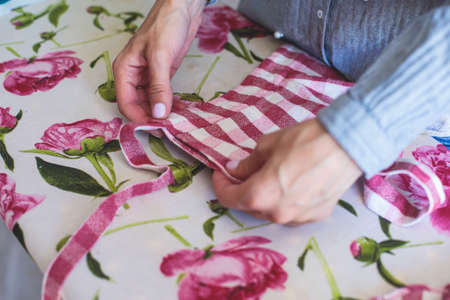 Process of hemming the dress and pants at home, close up of cloth on the sewing machine, hemming, tailoring, repairing and stitching cloth and dress, with the hand of female dressmakerの写真素材