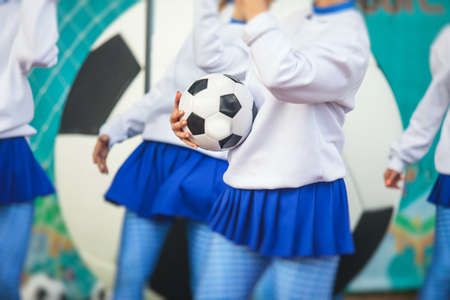 Female group of cheerleader in action, wearing white blue uniform with an audience in the background performing and supporting during football game matchの写真素材