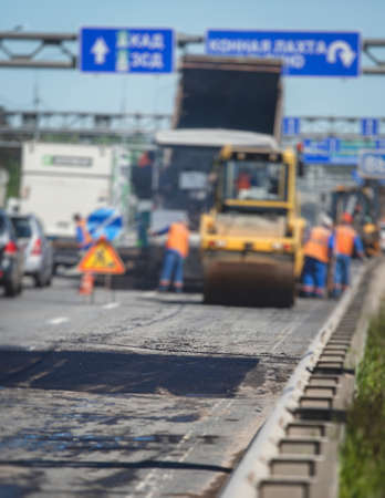 Process of asphalting and paving, asphalt paver machine and steam road roller during road construction and repairing works, workers working on the new road construction site, placing layer in summerの写真素材
