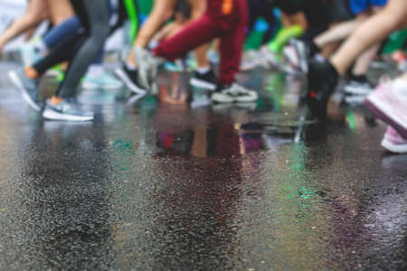 Marathon runners competition in the rain close-up, view of footwear running shoes during...