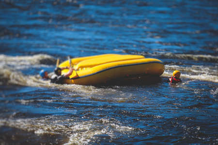 Boat is turned upside down during rafting extreme water sports with man drowning, concept of fail and solving problems, team work and survival, boat accident during kayaking and canoeing on a riverの写真素材