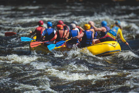 Raft boat during whitewater rafting extreme water sports on water rapids, kayaking and canoeing on a river, water sports team with a big splash of waterの写真素材