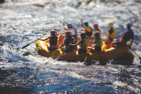 Raft boat during whitewater rafting extreme water sports on water rapids, kayaking and canoeing on a river, water sports team with a big splash of waterの写真素材