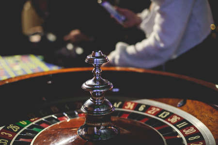 A close-up vibrant image of multicolored casino table with roulette in motion, with casino chips....