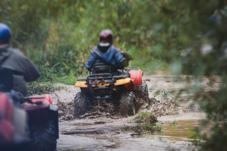 Group of riders riding atv vehicle on off road track, process of driving ATV vehicle, all terrain quad bike vehicle, during offroad competition, crossing mudの写真素材