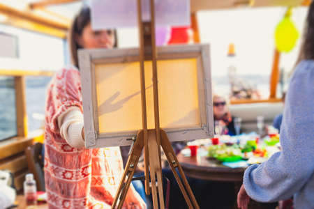 Process of painting, group class of adult talented students with paints easels, and canvases during lesson of watercolor painting outdoors, summer dayの写真素材
