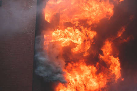 Massive large blaze fire in the city, brick factory building on fire, hell major fire explosion flame blast, with firefighters team firemen on duty, arson, burning house destructionの写真素材