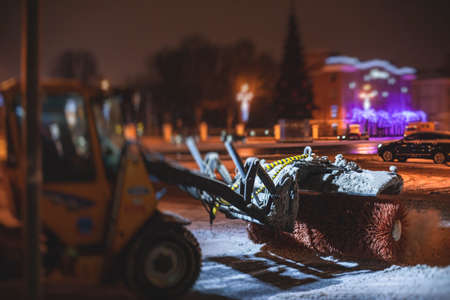 Process of snow removal on the city streets and roads with municipal vehicle, bulldozer, snowblower plow truck, snowplow, snow removal equipment in winter snowy nightの写真素材