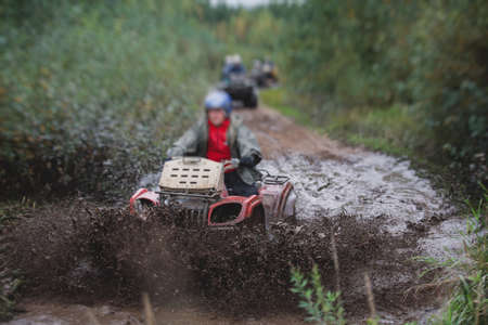Group of riders riding atv vehicle on off road track, process of driving ATV vehicle, all terrain quad bike vehicle, during offroad competition, crossing mudの写真素材