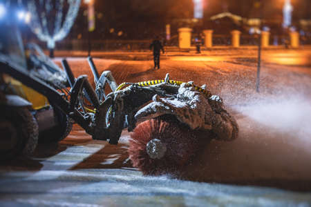 Process of snow removal on the city streets and roads with municipal vehicle, bulldozer, snowblower plow truck, snowplow, snow removal equipment in winter snowy nightの写真素材