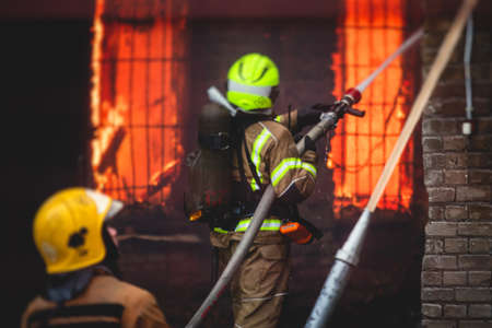 Firefighters put out large massive fire blaze, group of fire men in uniform during fire fighting...