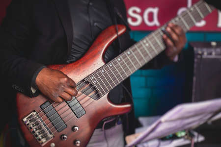 Concert view of an african-american musician and electric bass guitar player during band performing rock music, bassist player on stageの写真素材