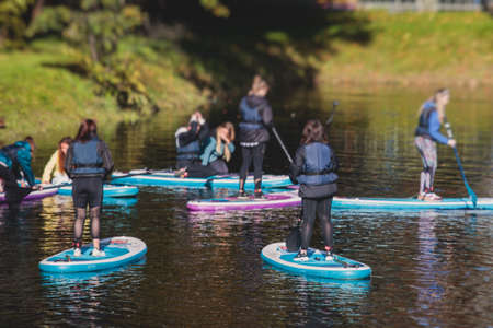 Group of sup surfers stand up paddle board, women stand up paddling together in the city river and canal in summer sunny dayの写真素材