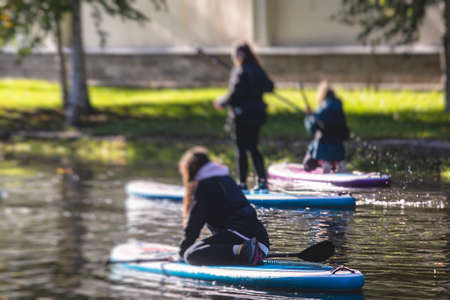 Group of sup surfers stand up paddle board, women stand up paddling together in the city river and...