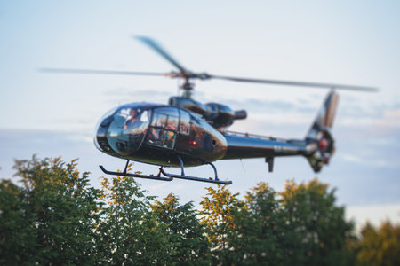 Civil black helicopter getting ready to fly, commercial charter private copter at helipad airfield with people embarking, pilot, getting a pilot course license, chopper landing on green grassの写真素材