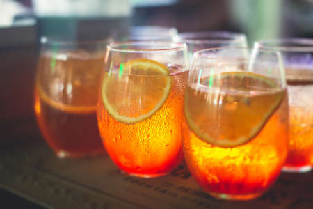Row line of red colored negroni and spritz aperitif alcohol cocktails on a party of alcohol setting on catering banquet table, and others on decorated catering table event with bartenderの写真素材