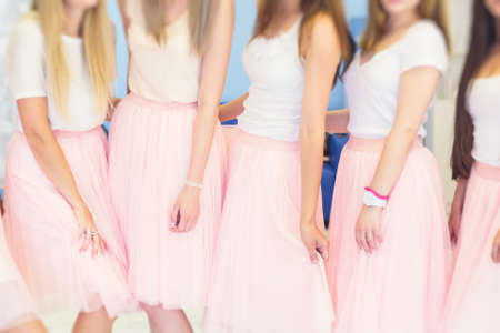 Happy young stylish multiethnic girls having fun during bachelorette bridesmaids party, group of diverse multiracial women dressed in the same colored dresses clothes, party in pink color tonesの写真素材