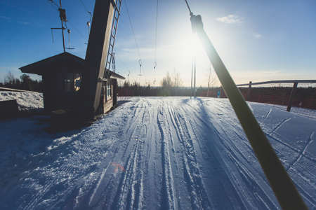 Beautiful cold mountain view of ski resort, sunny winter day with slope, piste and ski lift, with a group of mountain downhill skiers and snowboardersの写真素材