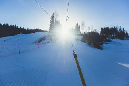 Beautiful cold mountain view of ski resort, sunny winter day with slope, piste and ski lift, with a group of mountain downhill skiers and snowboardersの写真素材