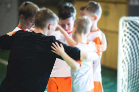 Junior young football team with a coach, group of kids children soccer team having training with...